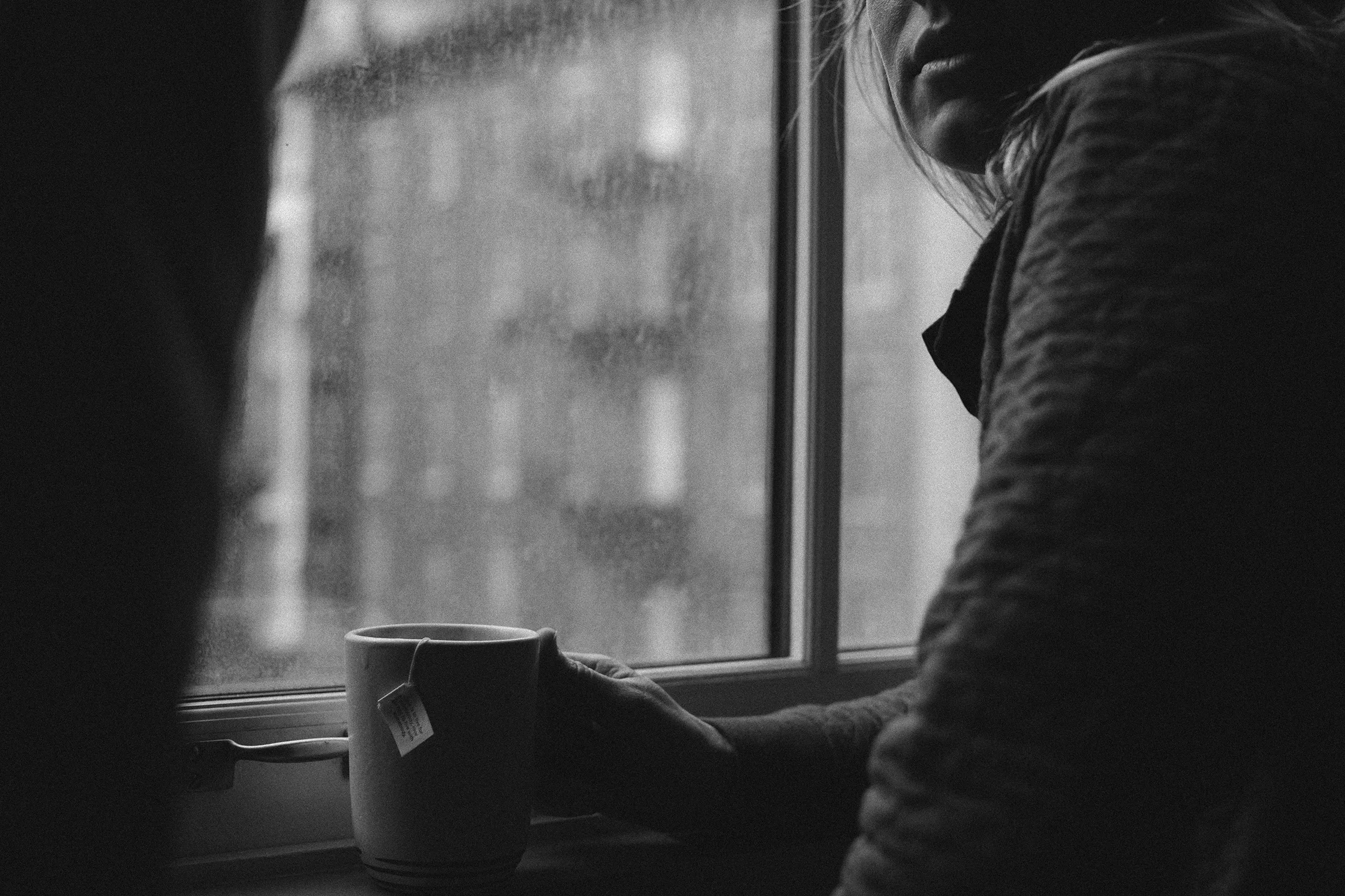 A woman holds a tea cup by a window