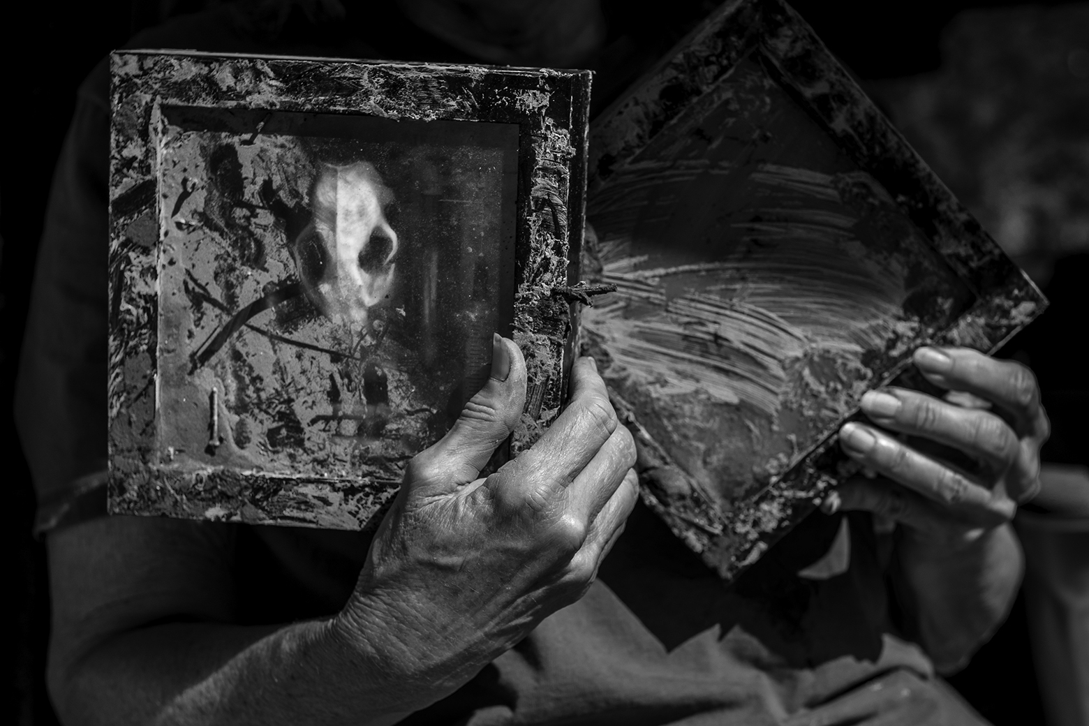 Hands holding up artwork covered in mud
