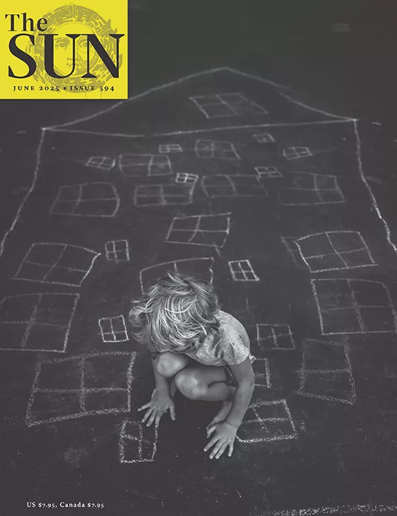 a child sitting on a pavement chalk drawing of a house 