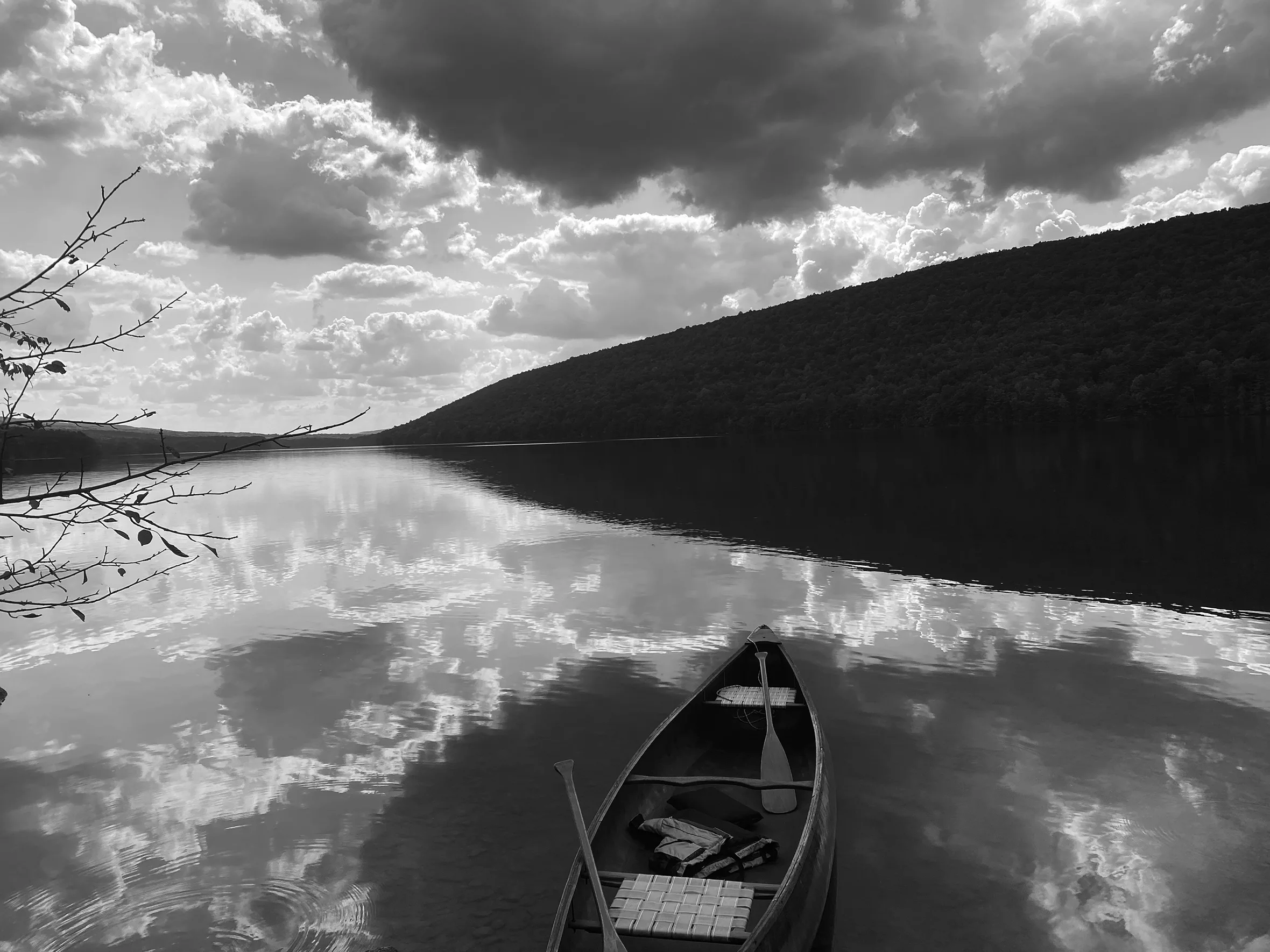 A canoe floats in a lake reflecting clouds