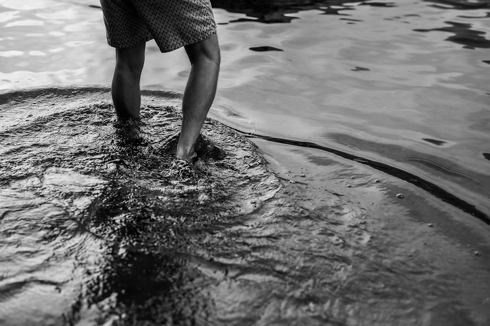 Bare feet standing in shallow water with ripple patterns. Interior photo for 'Brother, Electric' by Doug Crandell.