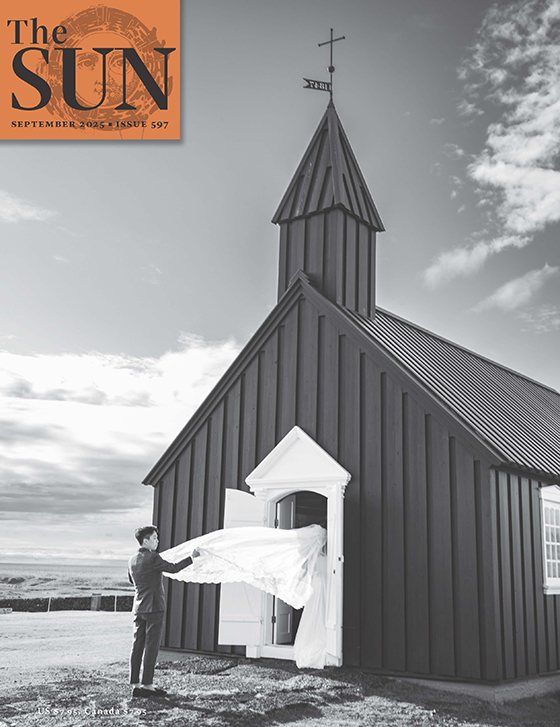 The Sun magazine September 2025 cover showing a person holding the end of a bride's veil as she walks into a church. Photo by Eric Davidove.