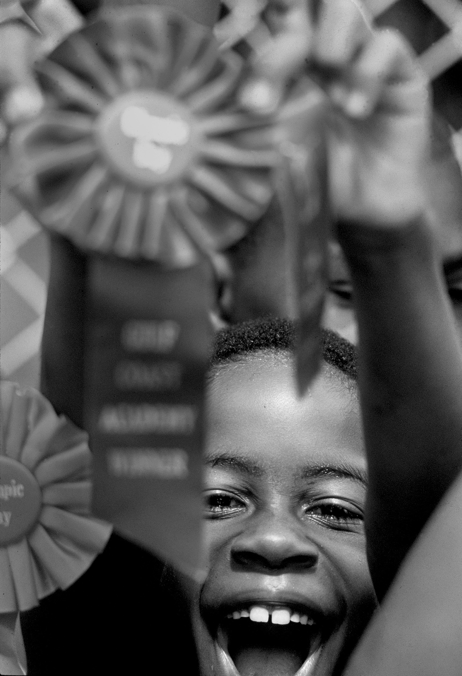 A smiling Black child holds up an award ribbon