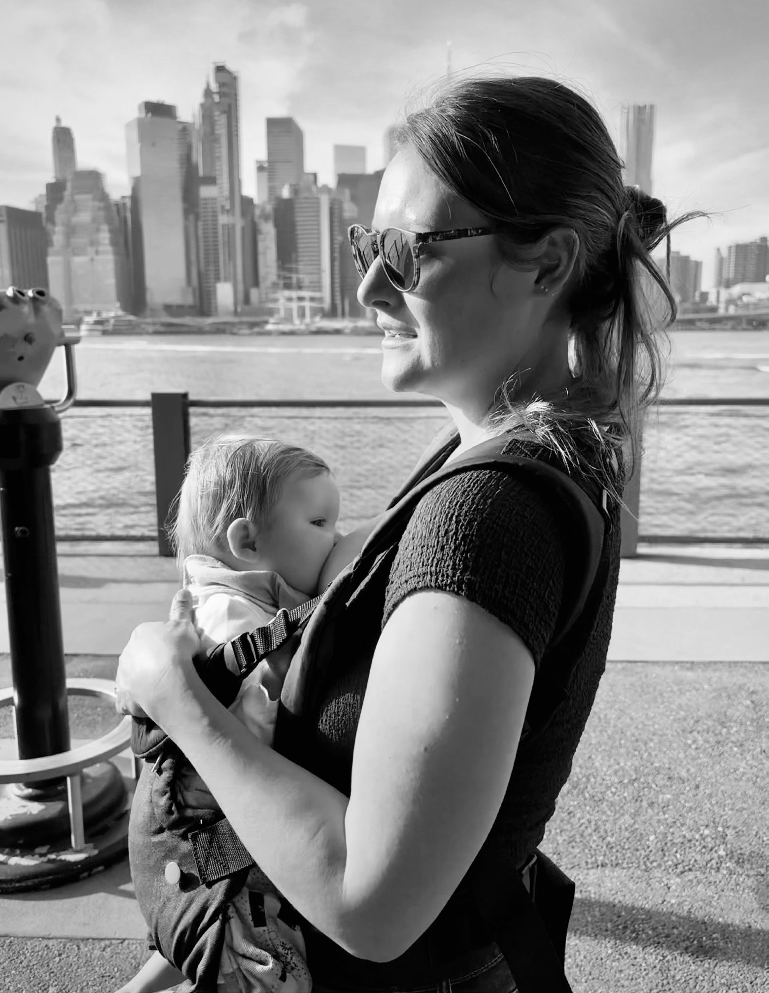 A woman breastfeeds a baby as she walks on an urban path in the city