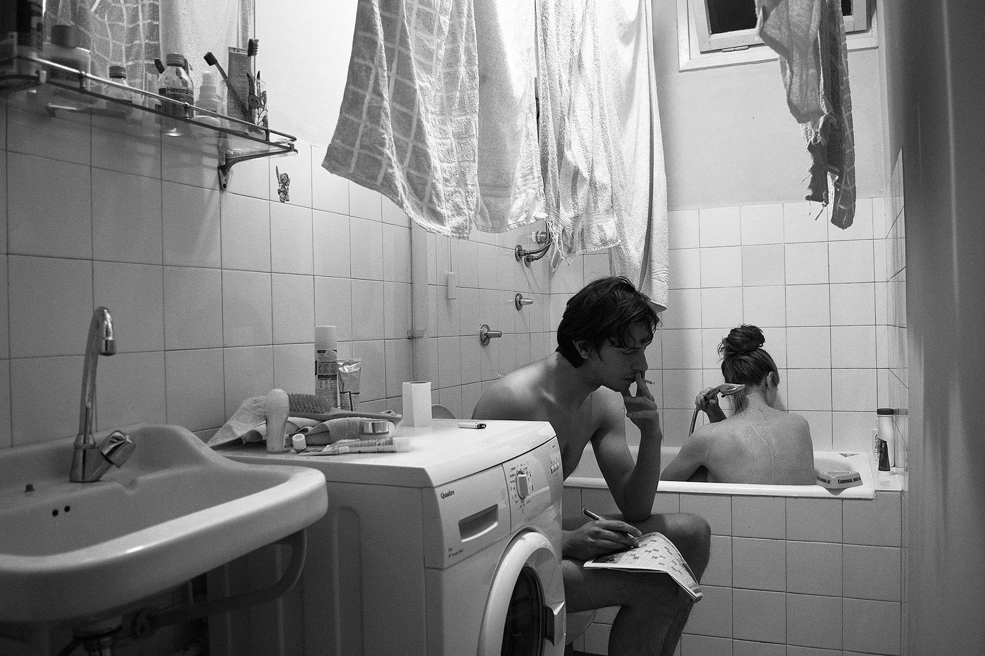Bathroom scene with person smoking and person bathing in background. Table of Contents page for August 2025 issue.