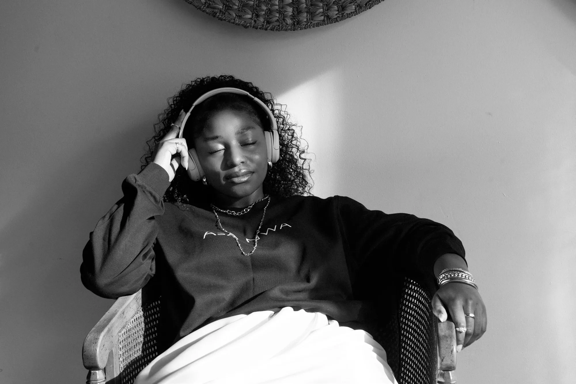 A young woman with her eyes closed listens to music through headphones