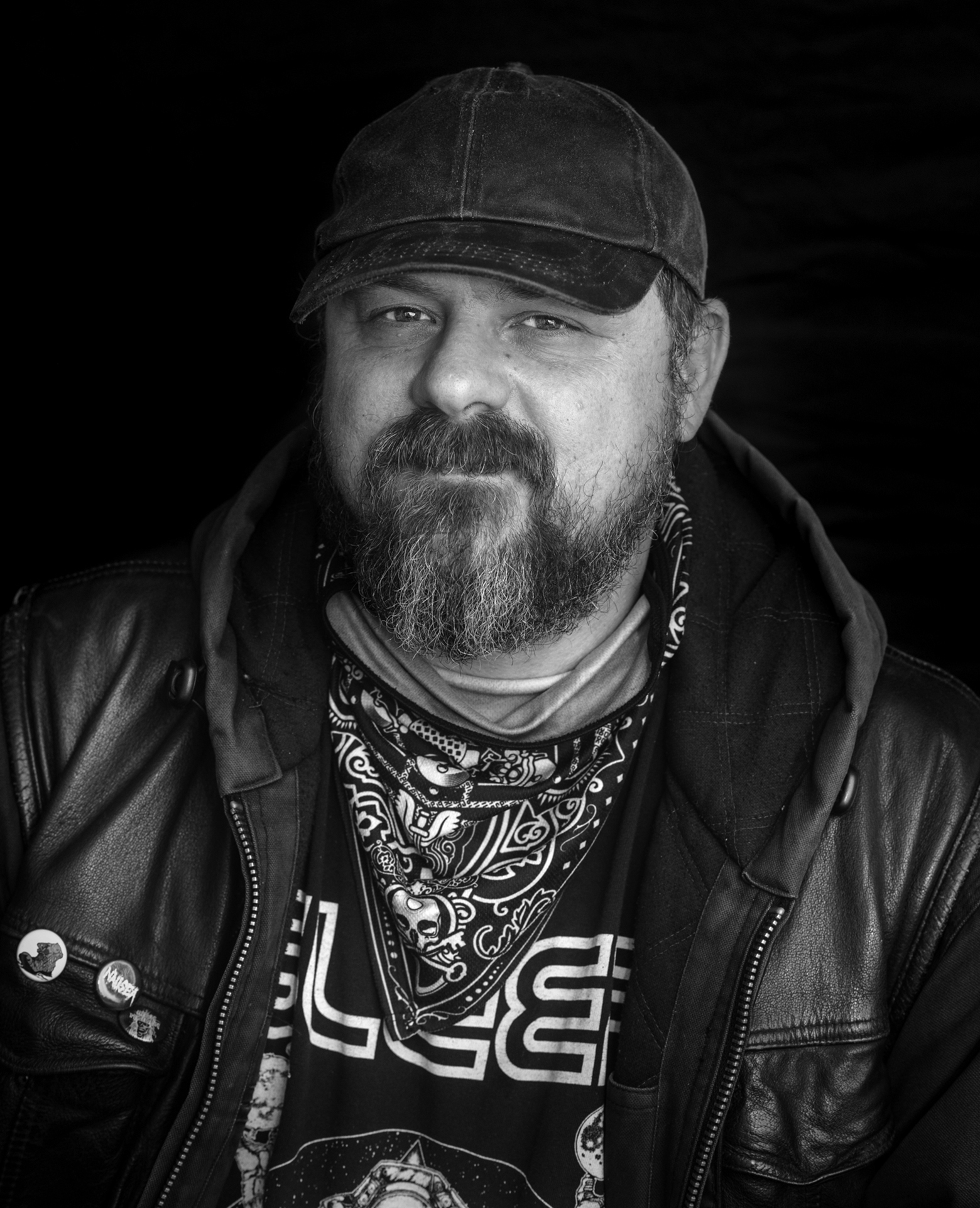 Graham Pruss wearing a black leather jacket. A handkerchief is around his neck and he’s wearing a dark denim ball cap.