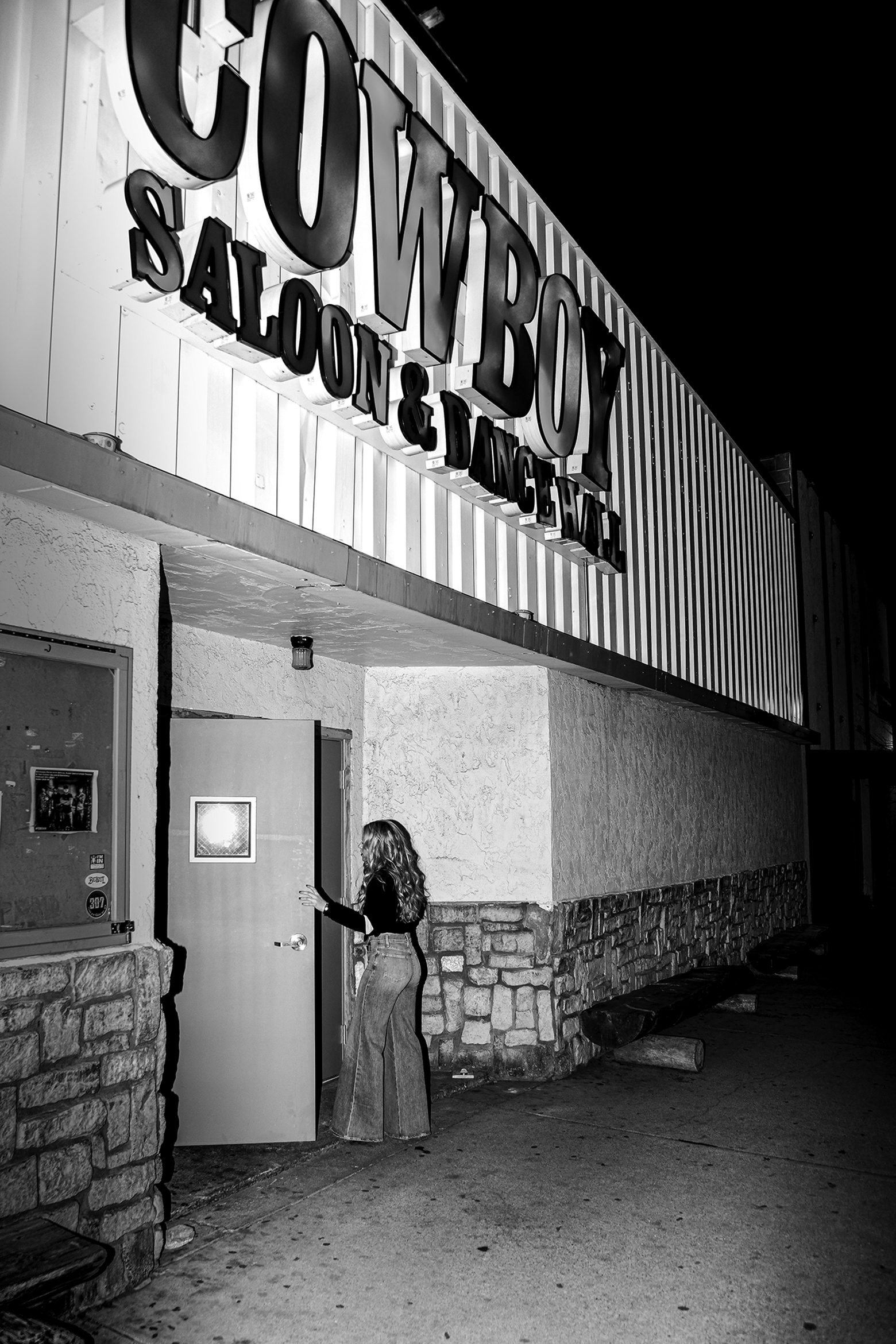 A woman entering the doors of a building labeled Cowboy Saloon and Dance Hall.